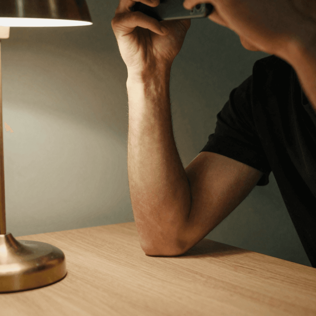 Photo of an elbow braced on a table, steadying the phone near an eye